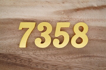 Golden Arabic numerals on a real brown and white wooden floor number 7358