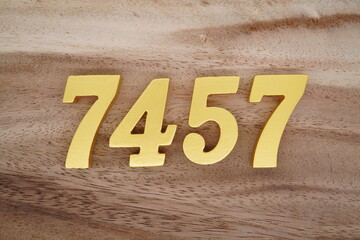 Golden Arabic numerals on a real brown and white wooden floor number 7457
