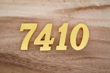 Golden Arabic numerals on a real brown and white wooden floor number 7410