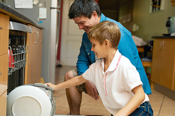 Teaching his son to tackle some chores. Shot of a father and son busy at a dishwashing machine.