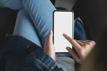 Mockup image of cell phone. Woman hand holding texting using blank white screen mobile phone. Female hipster in blue jeans using and looking at empty smartphone screen
