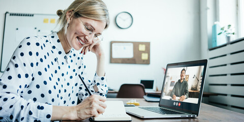 Smiling woman with googles has video call conference with her remote teammate. Laptop with camera...