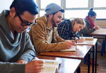 Sending texts during class. Cropped shot of a group of university students working in class while sitting in a lecture.