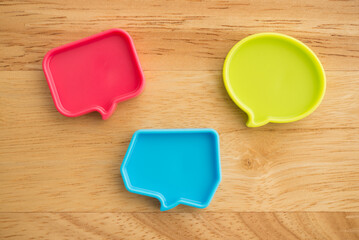 Chat bubbles on social media communication. Red, green and blue chat bubbles icon messages on wooden background minimal style. Social media online, social network concept.