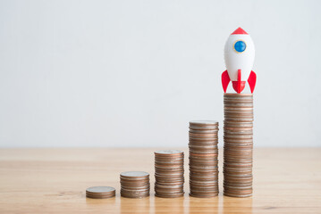 Startup project, creativity thinking idea, innovation and inspiration concept. Rocket launch on stacked coins to success goal on wooden background copy space minimal style.