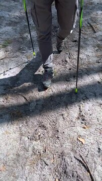 MĘŻCZYZNA UPRAWIAJĄCY NORDIC WALKING. SPACERUJĄCY MĘŻCZYZNA PO LESIE. SPACER PO LESIE W OKRESIE WIOSNY.