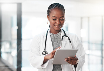 Who has time to be tied down to a desk. Shot of a young doctor using a digital tablet in a modern hospital. - Powered by Adobe