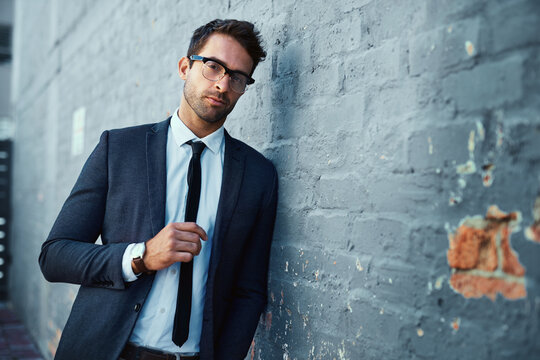 The concrete jungle is there to be conquered. Cropped portrait of a handsome young businessman standing against a grey facebrick wall.