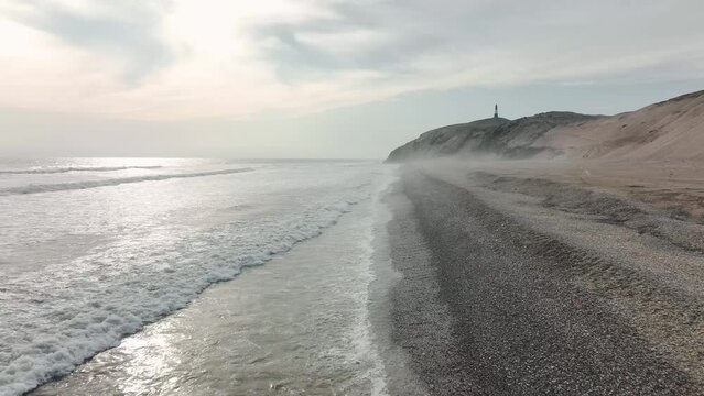 Aerial view of Media Luna Beach and lighthouse. Low flight over the waves, mystical atmosphere. Puerto Eten, Lambayeque, Peru.