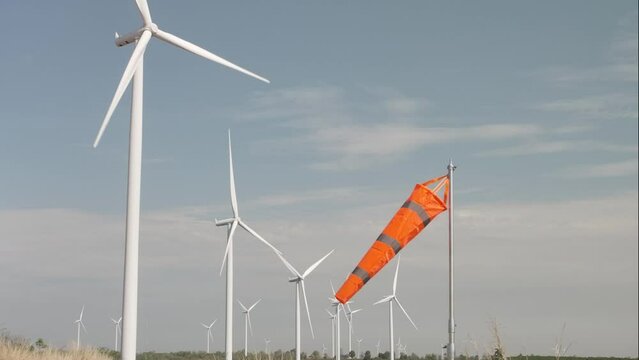  Slow motion Windmill rotating in Wind Turbine field with orange wind sock , Green energy and Renewable energy concept