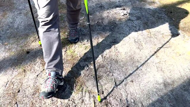 MĘŻCZYZNA UPRAWIAJĄCY NORDIC WALKING. SPACERUJĄCY MĘŻCZYZNA PO LESIE. SPACER PO LESIE W OKRESIE WIOSNY.