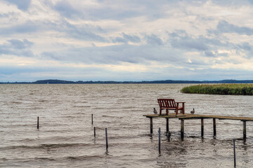 A wooden pier with a bench on the coast of the Krumminer Wiek in Neeberg, Mecklenburg-Western...