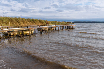 A wooden pier with a boat and some benches on the coast of the Krumminer Wiek in Neeberg,...