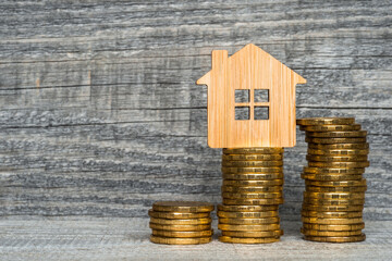 Bamboo house with yellow coins in the form of a close-up graph on a wooden gray background. The...