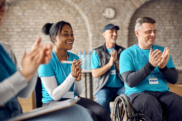 Group of happy volunteers clapping hands after successfully collecting donations at center for humanitarian aid.