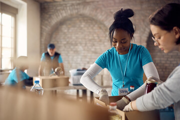Young happy African American woman volunteering at food bank.