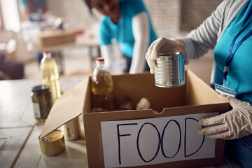 Close up of volunteer packing donation boxes while working at food bank.