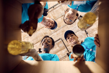 Below view of volunteers packing donated food in cardboard box.