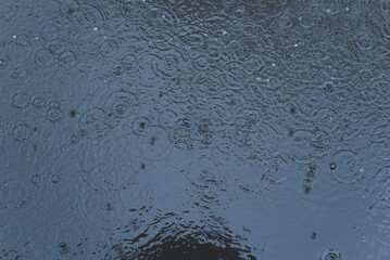 Top view dark water surface with raindrops, rain shower outdoors