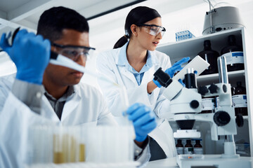 Hard at work in the name of health. Shot of two young scientists using a digital tablet while...