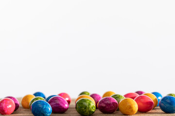 Colorful Easter eggs arranged on linen fabric and white background. Easter.