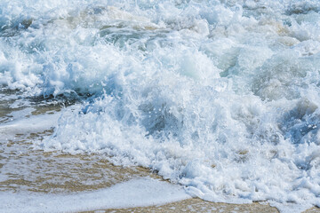 Close-up of a wave with white splashes crashing onto a beach in Florida