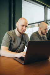 Fototapeta premium Unshaven happy man using laptop while sitting in cafe
