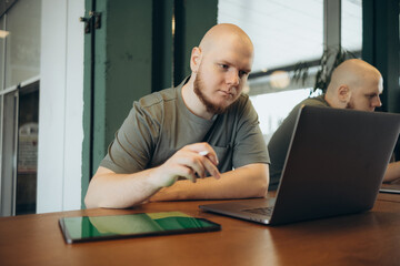 Fototapeta na wymiar Unshaven happy man using laptop while sitting in cafe