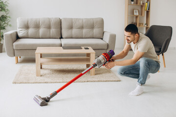 Young man doing vacuuming in the apartment