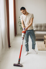 Young man doing vacuuming in the apartment