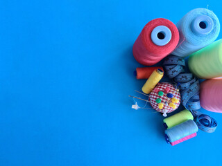 Multicolored thread needles and centimeter on blue background