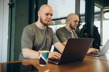 Fototapeta premium Unshaven happy man using laptop while sitting in cafe