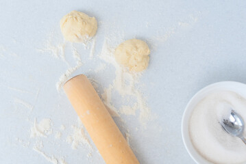 Dough, flour, rolling pin and bowl with sugar on a white kitchen table. Selective focus. Preparation for making pies with apple filling. Cooking at home concept. Tradition home-made food
