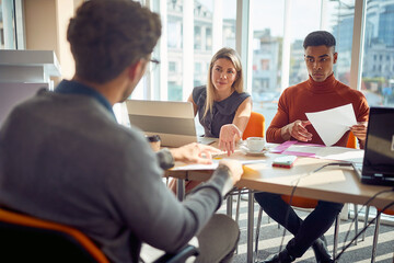 Young colleagues in a commission having an interview with a male applicant for a job. Business, people, company