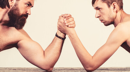 Two man's hands clasped arm wrestling, strong and weak, unequal match. Heavily muscled bearded man...