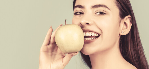 Stomatology concept. Woman with perfect smile holding apple, blue background. Woman eat green apple. Portrait of young beautiful happy smiling woman with green apples. Healthy diet food