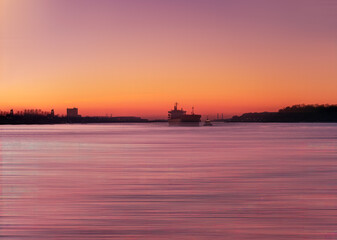 Fototapeta premium Hamburg Elbe burning sunset view with a boat moving as a silhouette