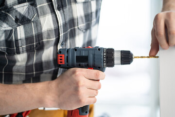 Furniture master drilling chipboard with drill in light room