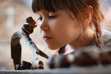 Foto op Aluminium Little girl intently watching small snail crawling along wooden bench while spending time in nature © shangarey
