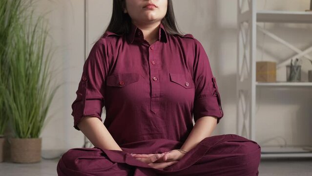 Meditating woman. Yoga practice. Healthy lifestyle. Relaxed female exercising on floor in lotus pose mudra dhyana gesture at home.