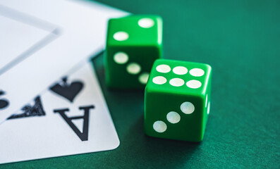 Green dice and playing cards on poker table