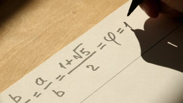 Young mathematician hand writes formula for a golden ratio on the paper. Date of shooting day 23 March 2022 year, MSK time. This video was filmed in Russia.