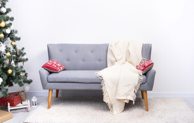 Gray sofa with festive pillows standing in room with christmas tree
