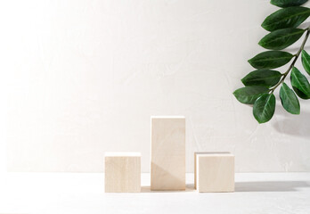 Wooden square Podium stand on a beige background with a green branch in the background