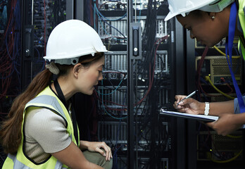 Lets make a note and come back to it. Cropped shot of two attractive female programmers working in a server room.