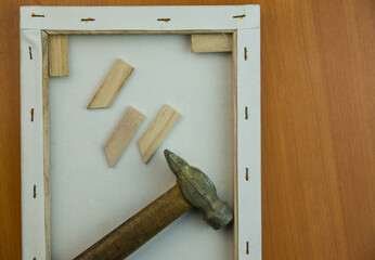 Frame with stretched canvas, hammer wooden spacers to prepare the canvas on the painting. Art...