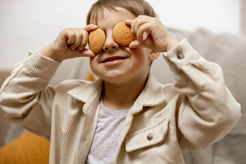 Portrait of little adorable boy holding two biscuits. Kid with cookies. Child and gluten. Healthcare, gluten intolerance by kids. Preschool child with casual clothing. Smile, positive emotions. - obrazy, fototapety, plakaty