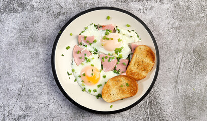 Easy breakfast - fried eggs and sausages with toast on a round plate on a dark gray background. Top view, flat lay  .