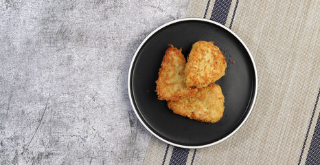 Traditional Hash brown potato fried pancakes on a round plate on a dark gray background. Top view, flat lay