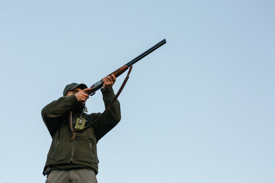 Male hunter with rifle aiming on bird in nature
